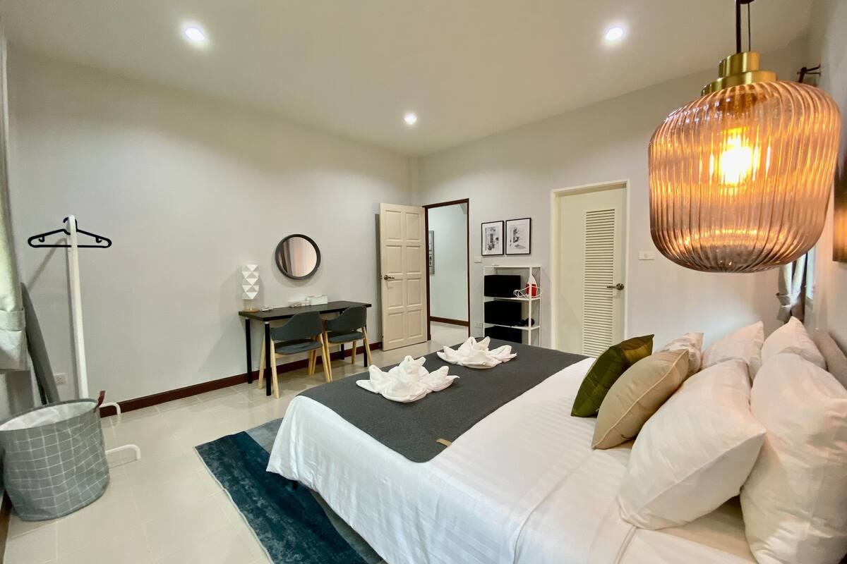 A modern bedroom with a bed, bedside table, and a desk with chairs.