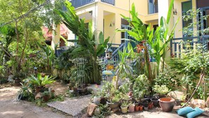 A courtyard with various potted plants, a small garden area, and a building with balconies. - Baan Patcharintorn Samui (Koh Samui)