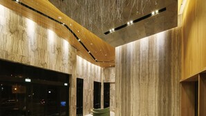 Un vestíbulo amplio con piso de mármol, detalles de madera y una lámpara colgante.