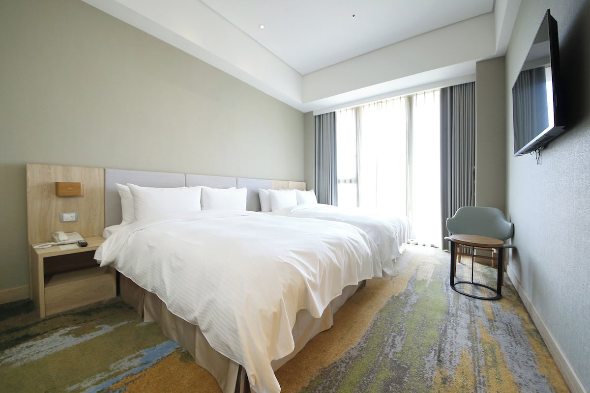 Una habitación de hotel con una cama grande, una mesita de noche y una silla.