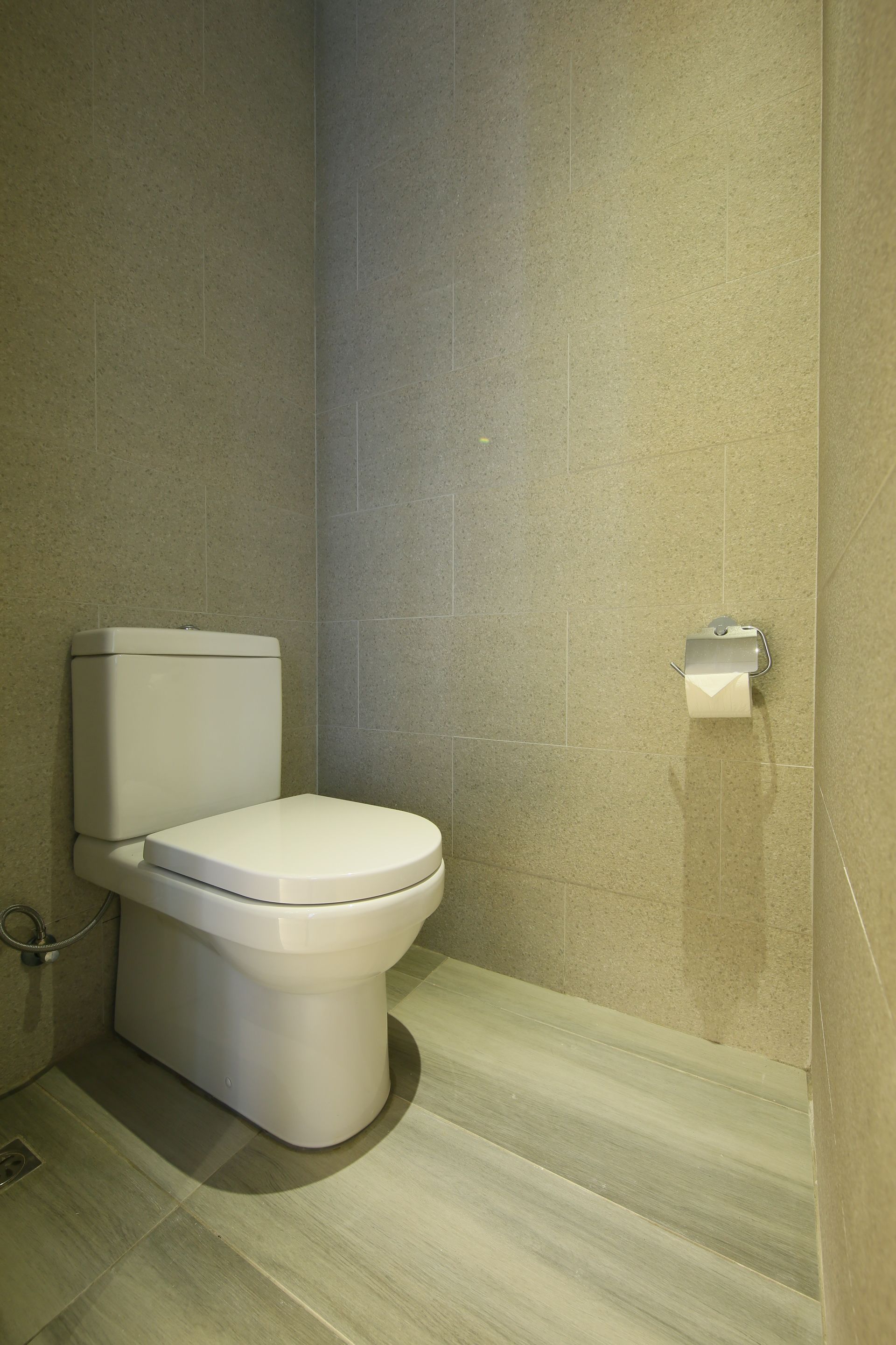 Ein modernes Badezimmer mit Toilette, Toilettenpapierhalter und Duschbereich.