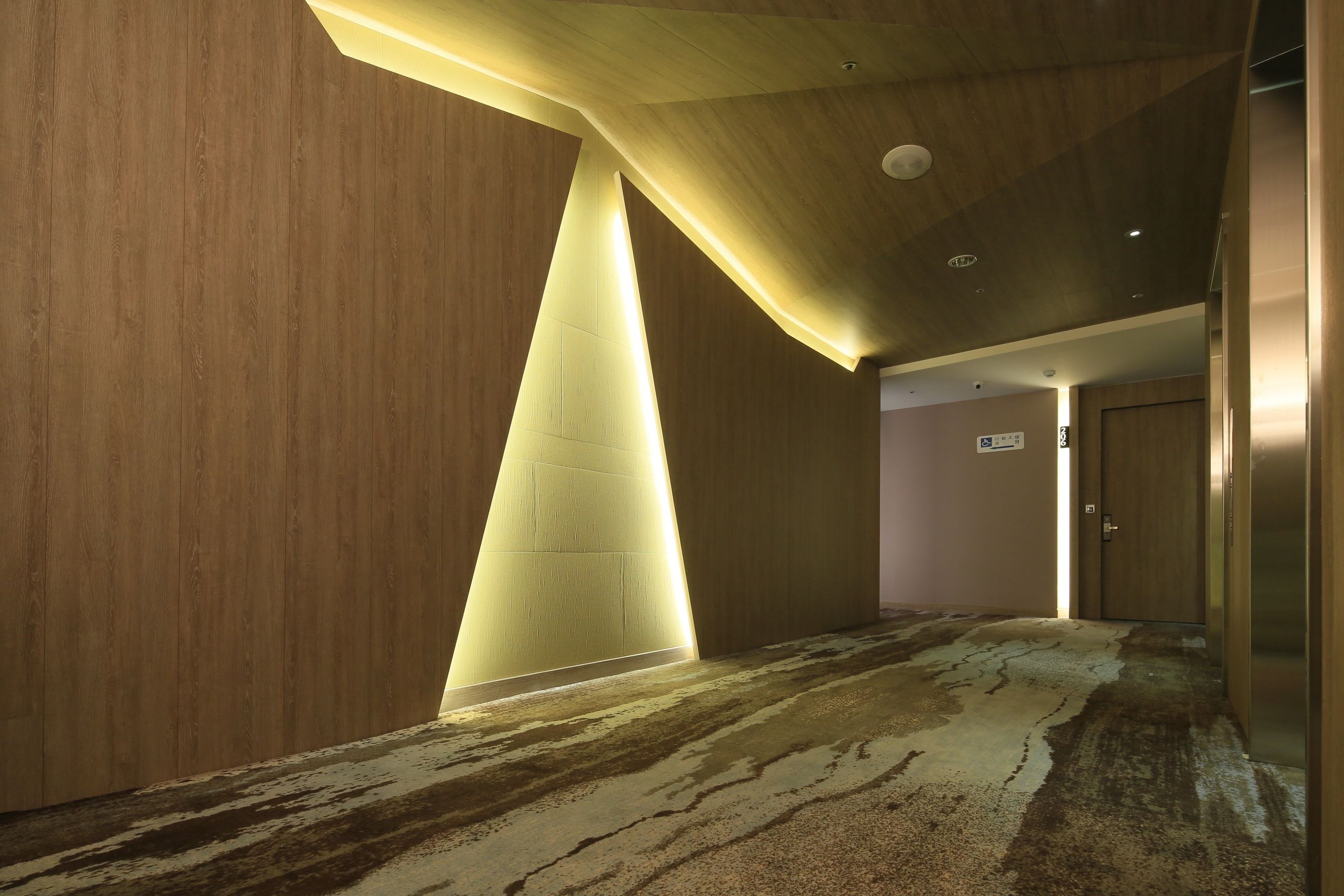 A hallway with wooden walls, a carpeted floor, and a door at the end.