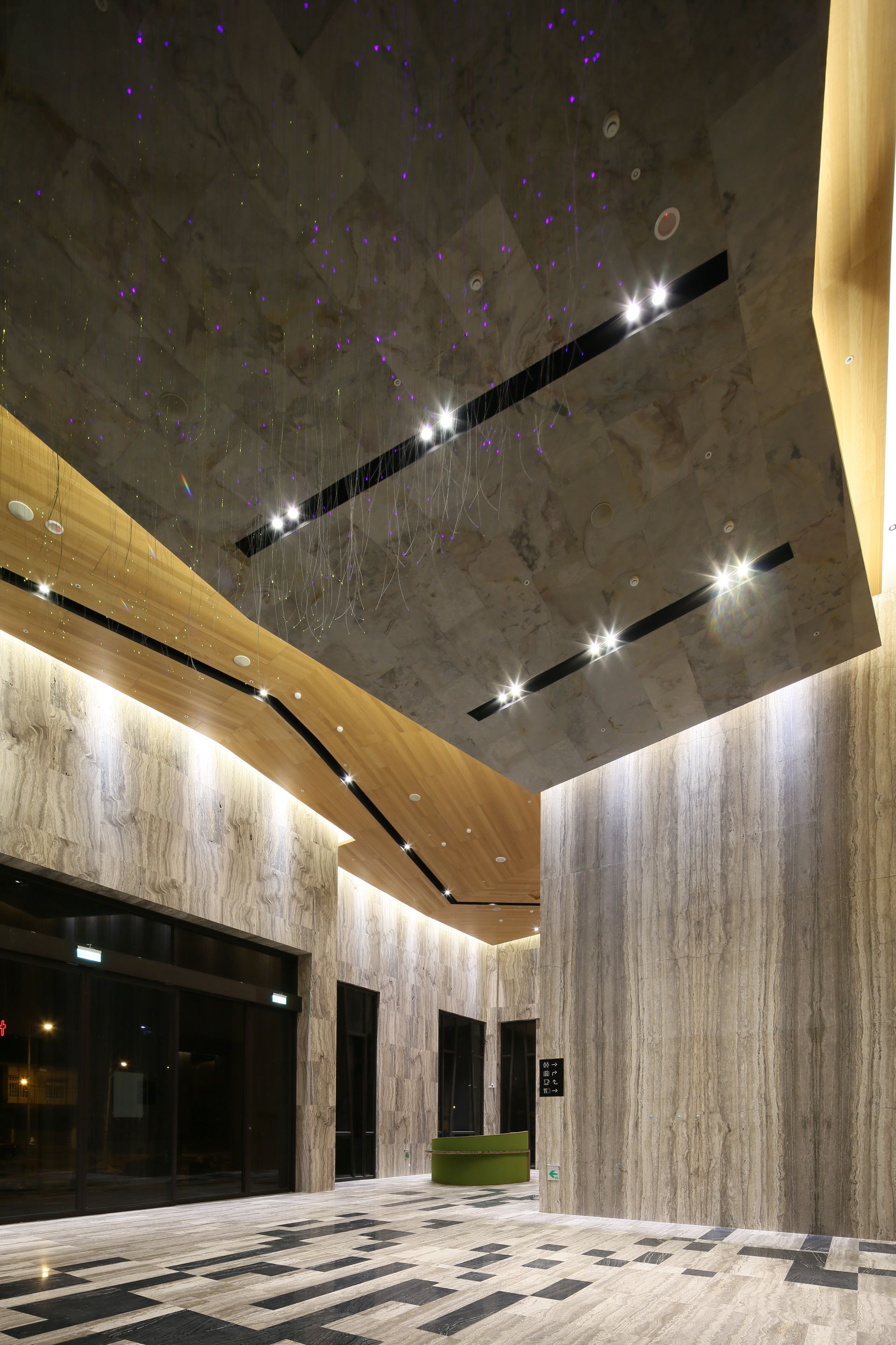 A spacious lobby with a high ceiling, modern lighting fixtures, and a checkered floor pattern.