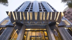 Un edificio moderno con una fachada geométrica única y un amplio acceso de vidrio.
