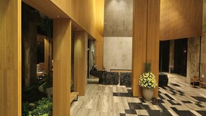 Un vestíbulo moderno con paneles de madera, un mostrador de recepción y una mesa de registro.