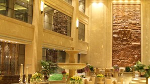 A spacious lobby with a fountain, seating areas, and a large decorative wall.