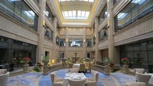 A spacious atrium with a high ceiling, a central fountain, and a round table set for dining surrounded by chairs.