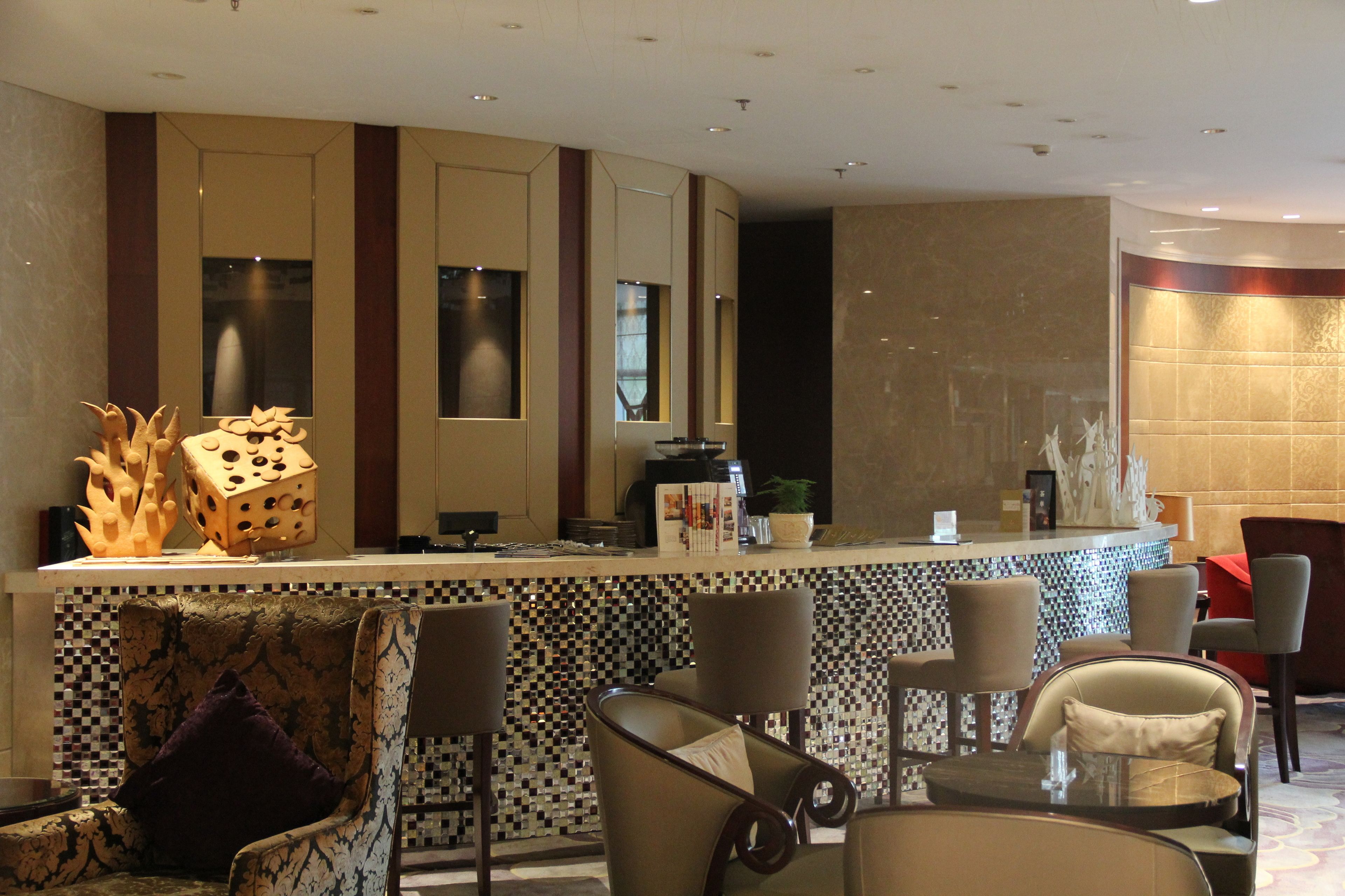 A modern bar area with a checkered tile backsplash, bar stools, and a decorative centerpiece.