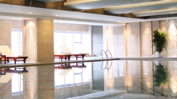 A spacious lobby with a reflective floor, seating areas, and a large plant.