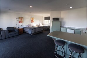 A compact hotel room with a kitchenette, a bed, a sofa, and a small bar area. - Alexandra Heights Motel (Alexandra)