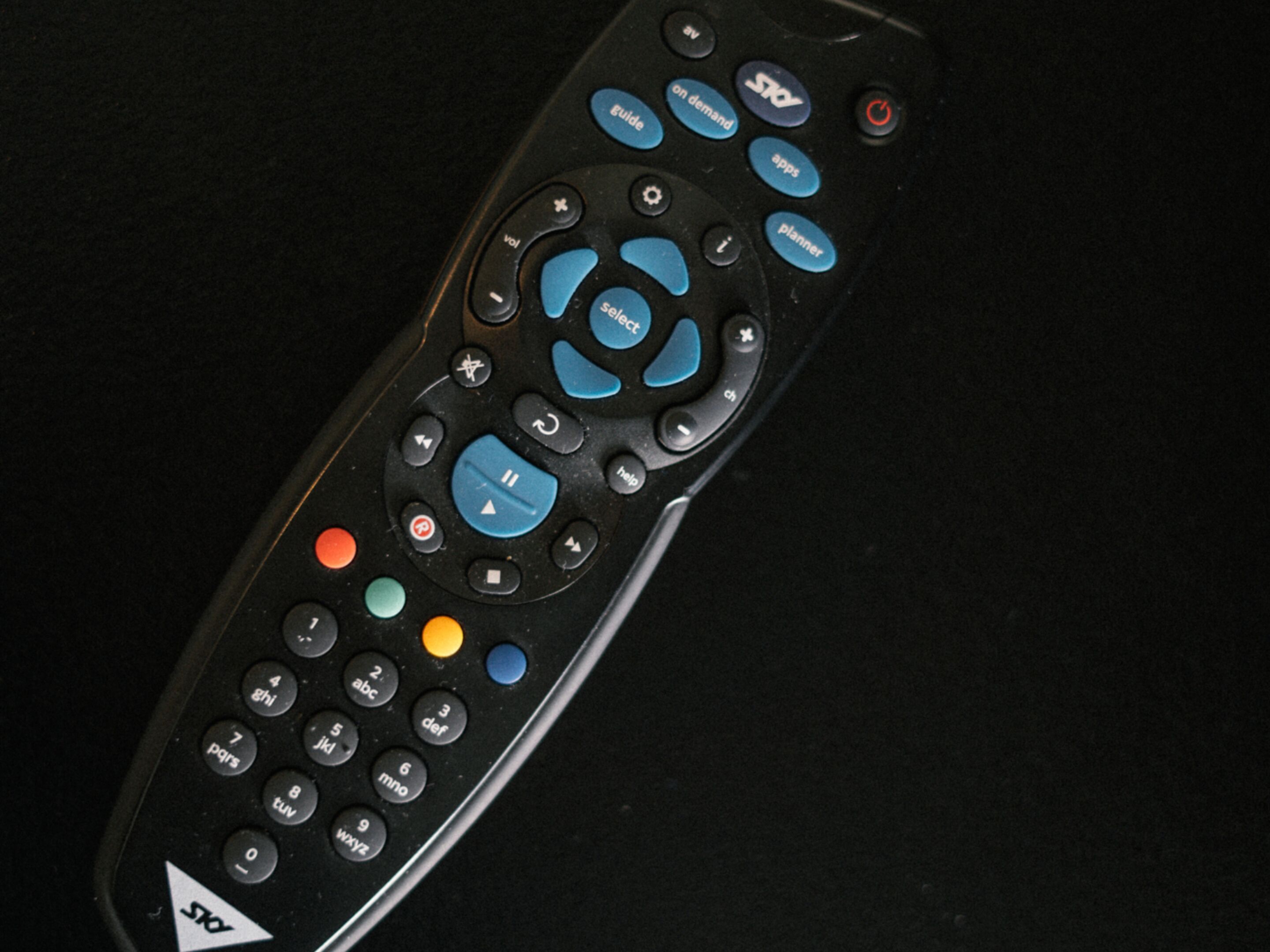 Un control remoto con varios botones, incluyendo controles de dirección, volumen y canal.