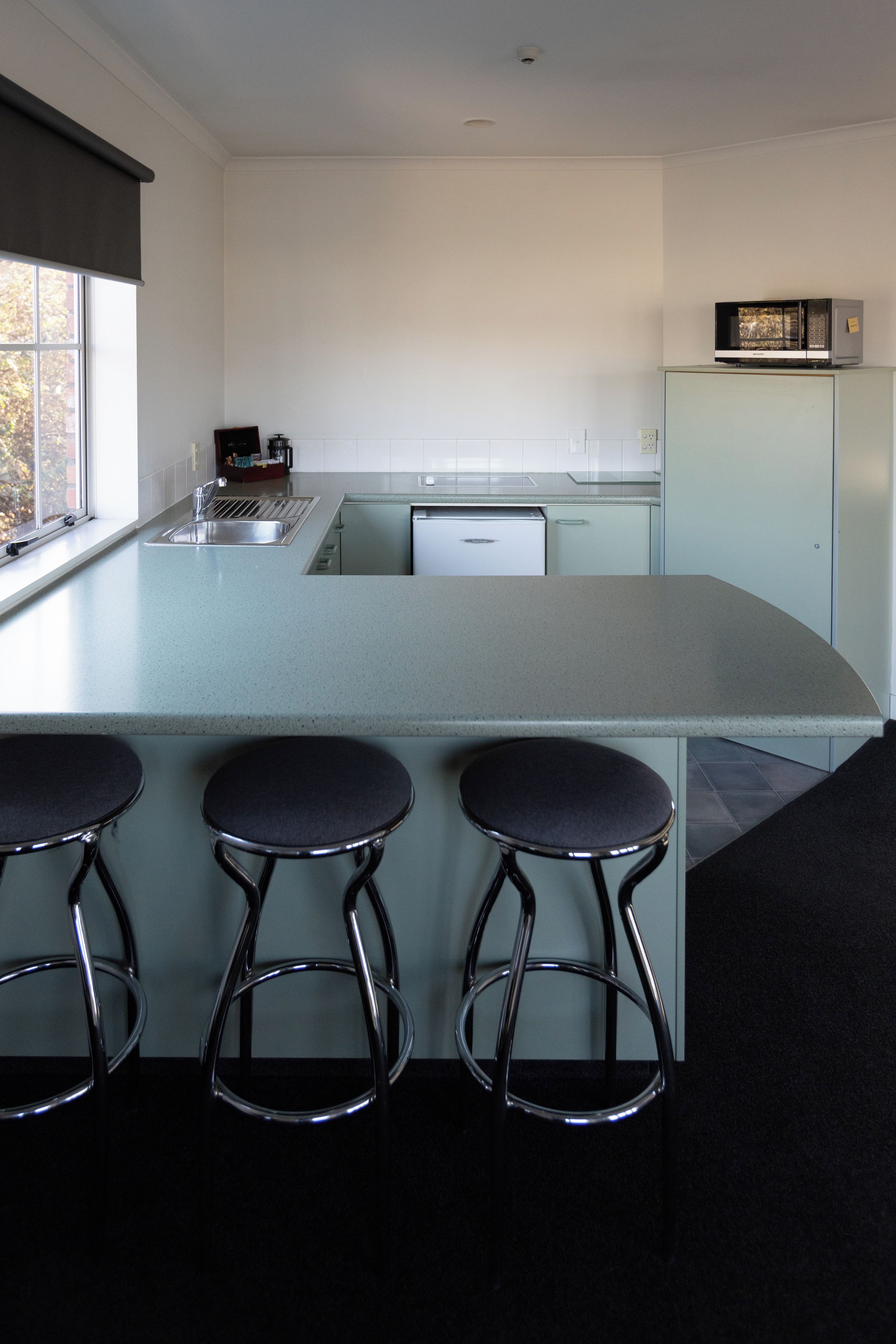 Una cocina moderna con una isla grande, taburetes de bar y un microondas en la encimera.