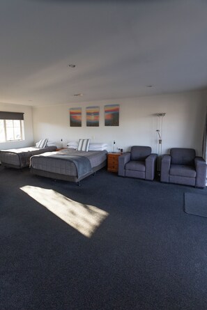 Une chambre spacieuse avec un grand lit, deux tables de chevet, une commode et un coin salon comprenant une chaise et un canapé.