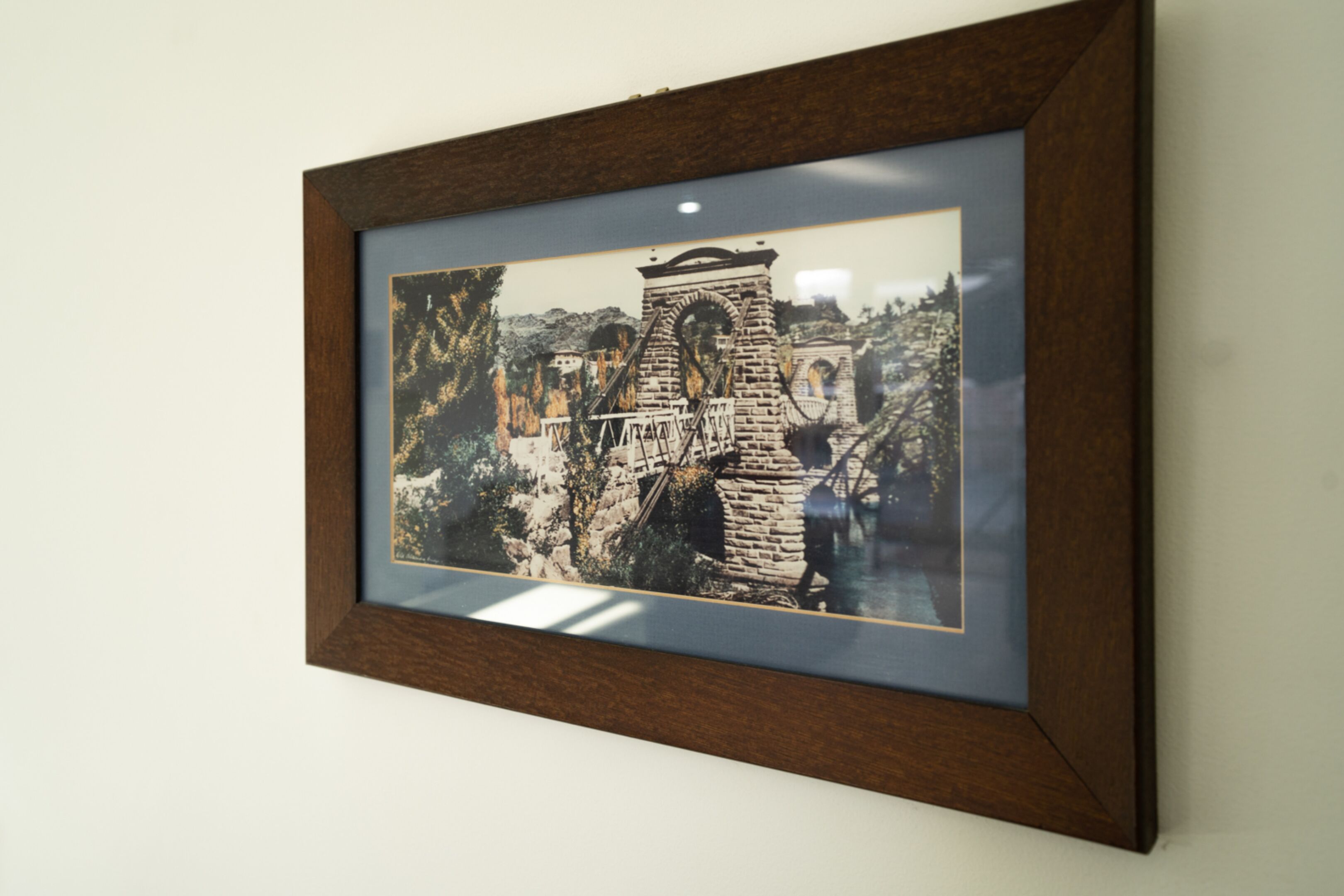 Fotografía enmarco de una estructura de piedra histórica con arcos y una escalera, presumiblemente una ruina, con un fondo de árboles y cielo despejado.
