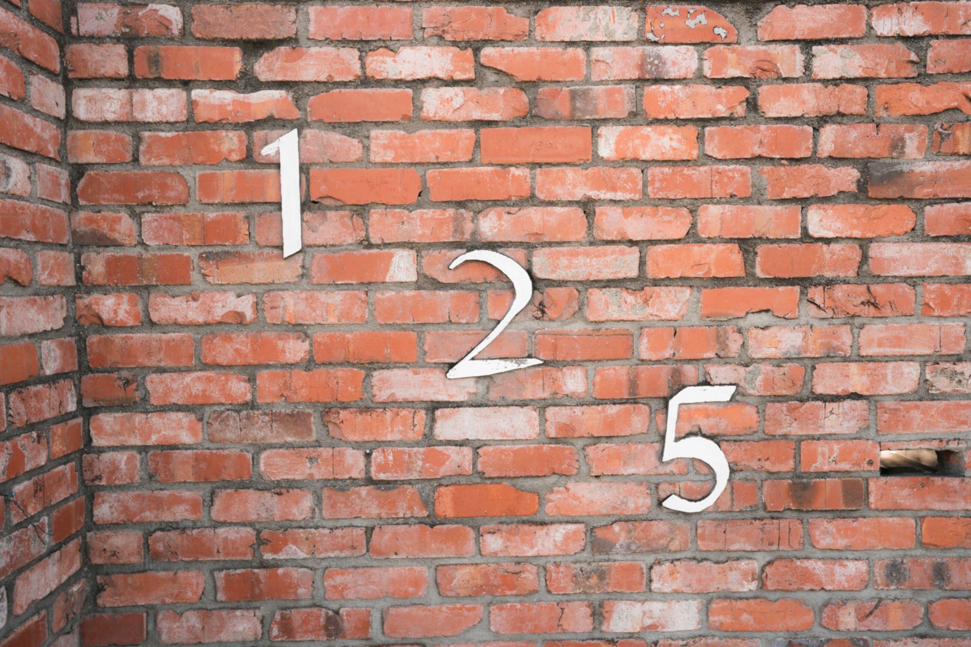 Una pared de ladrillo con los números del 1 al 5 pintados.