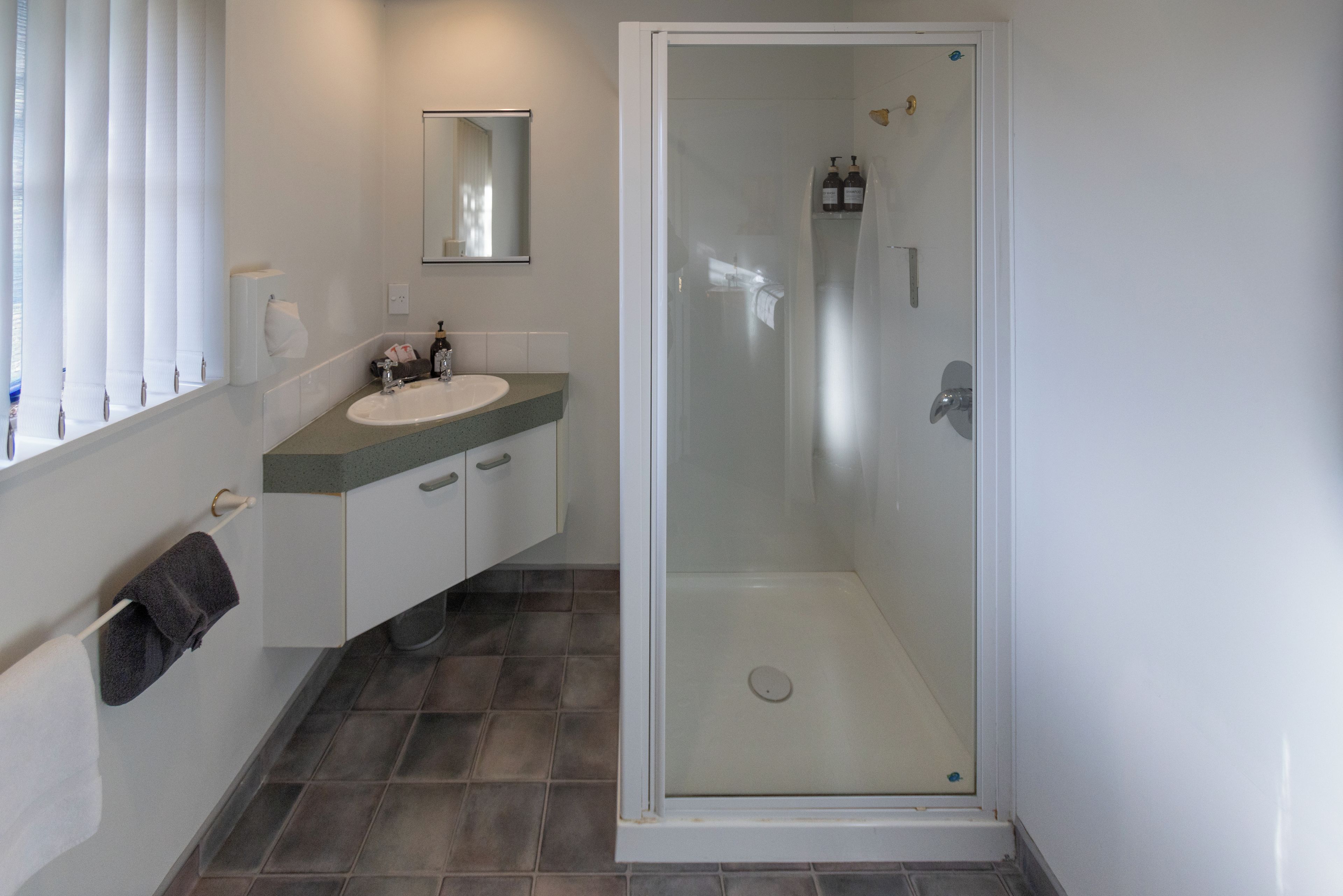 Ein Badezimmer mit einer Duschkabine, einem Waschbecken und einem Spiegel.