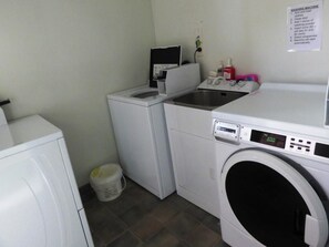 A laundry room with a washing machine, a dryer, and a small sink. - Alexandra Heights Motel (Alexandra)