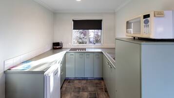 Una cocina compacta con ventana, microondas y refrigerador.
