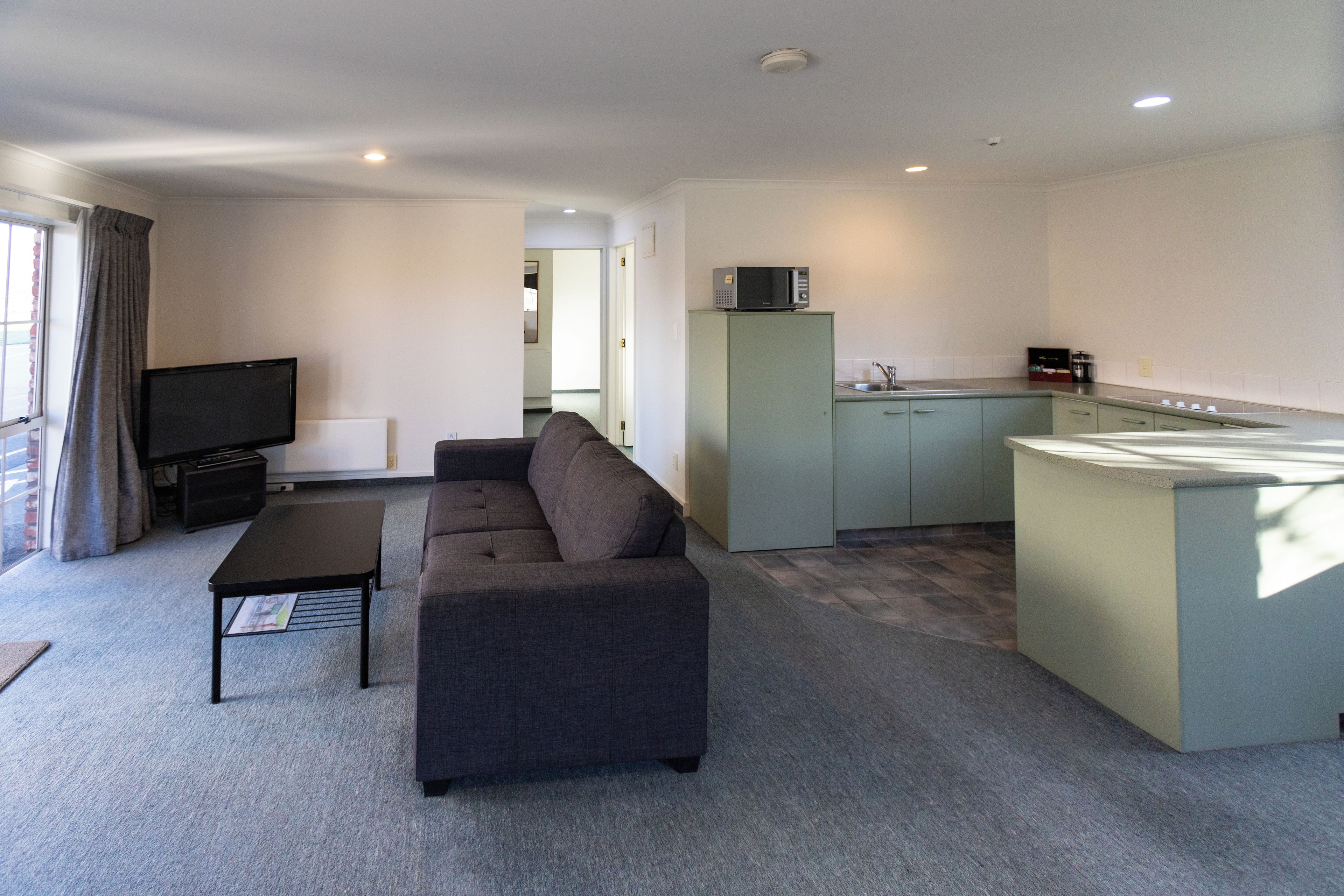 A compact living space with a sofa, a television, a kitchenette, and a dining area.