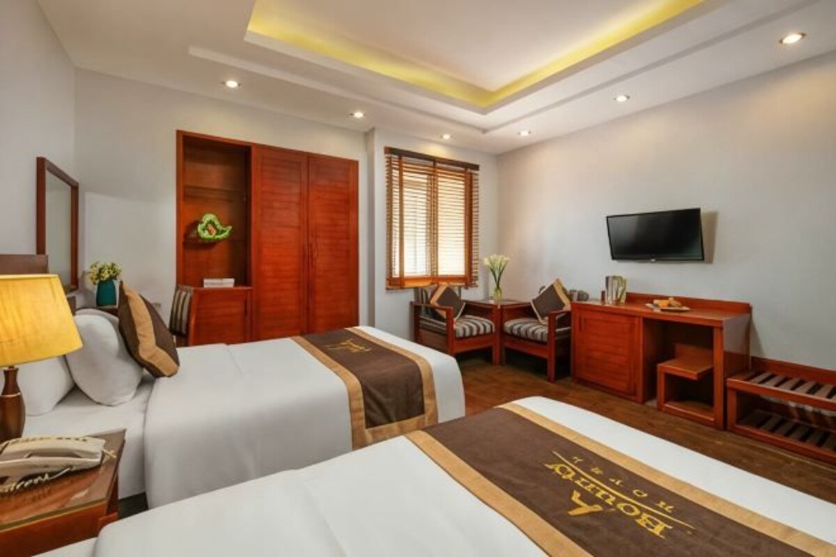 A hotel room with two beds, a desk, a TV, and a wardrobe.