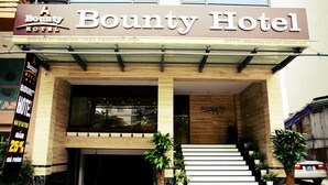 The entrance of Bounty Hotel with a modern facade, a staircase leading to the entrance, and potted plants at the base. - Bounty Hotel (Hanoi)