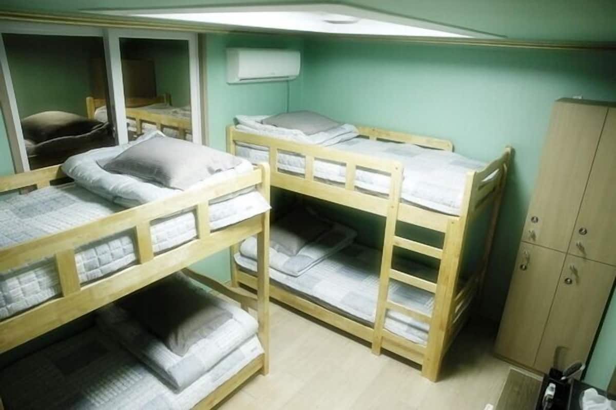 Een slaapkamer met een stapelbed, een houten garderobe en een bureau.