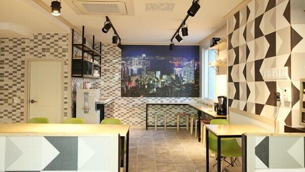 Un restaurante moderno con un mural de la ciudad, paredes con patrones geométricos y una zona de bar.