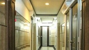 Un pasillo con piso de baldosas brillantes, puertas de madera y una lámpara en el techo.