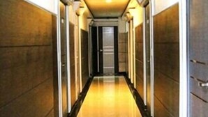 Un pasillo largo y estrecho con piso brillante, bordeado por paredes con textura.