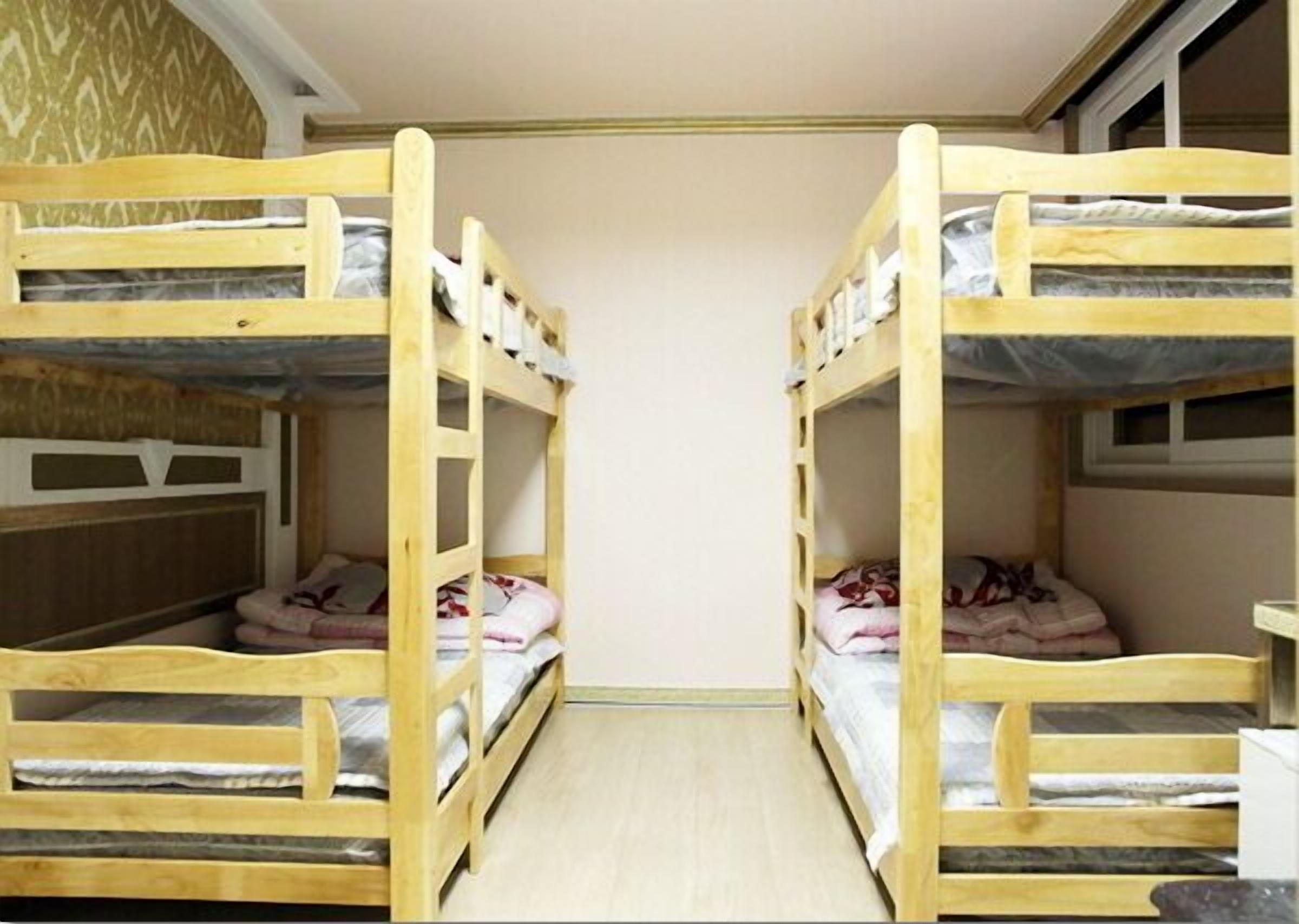 A room with two bunk beds, a small table, and a patterned wall.