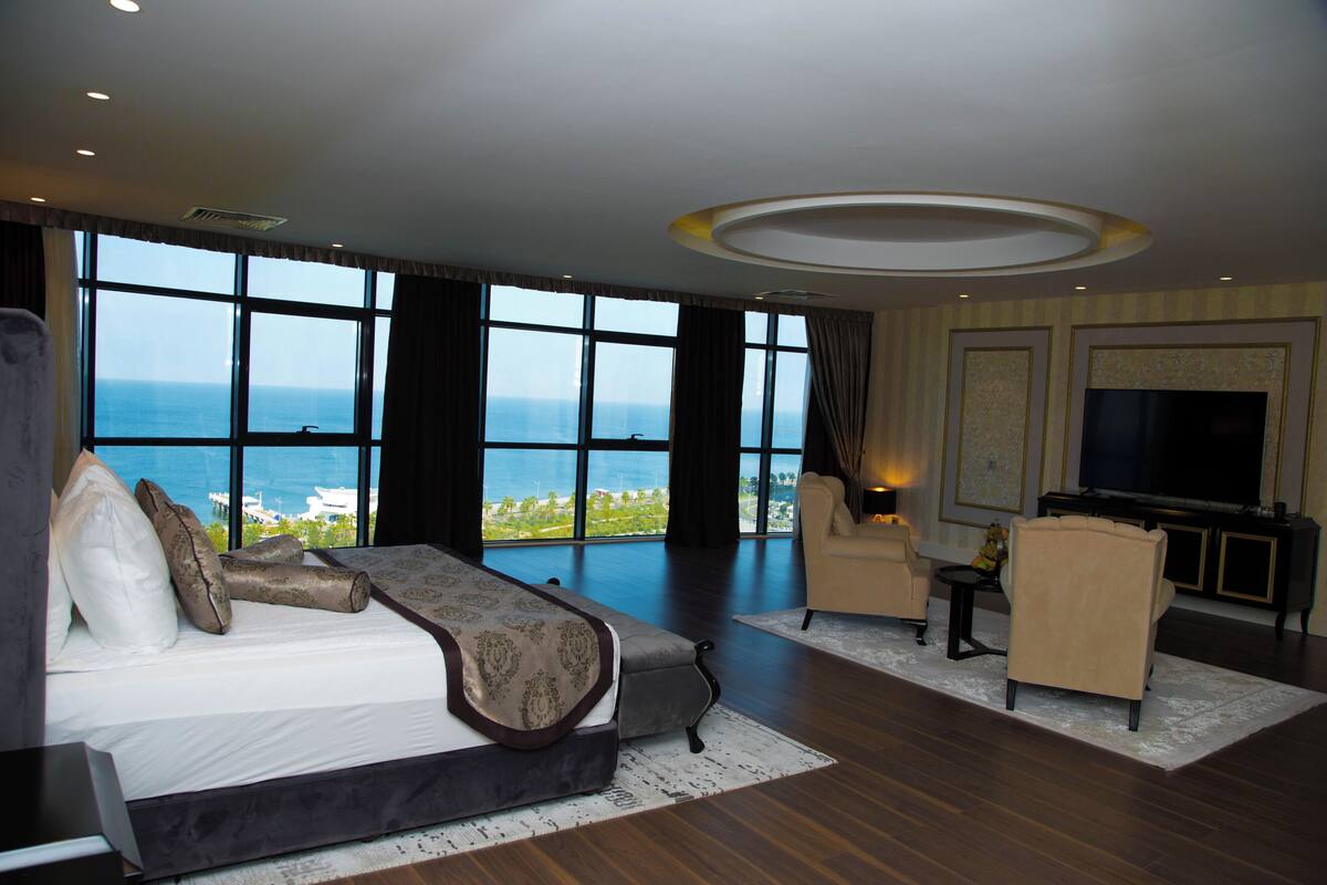 Un dormitorio espacioso con una cama grande, televisión y vistas al océano.