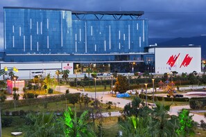 A modern building with a reflective glass facade, a large billboard, and a landscaped area with trees and a playground. - Euphoria Hotel Batumi (Batumi)