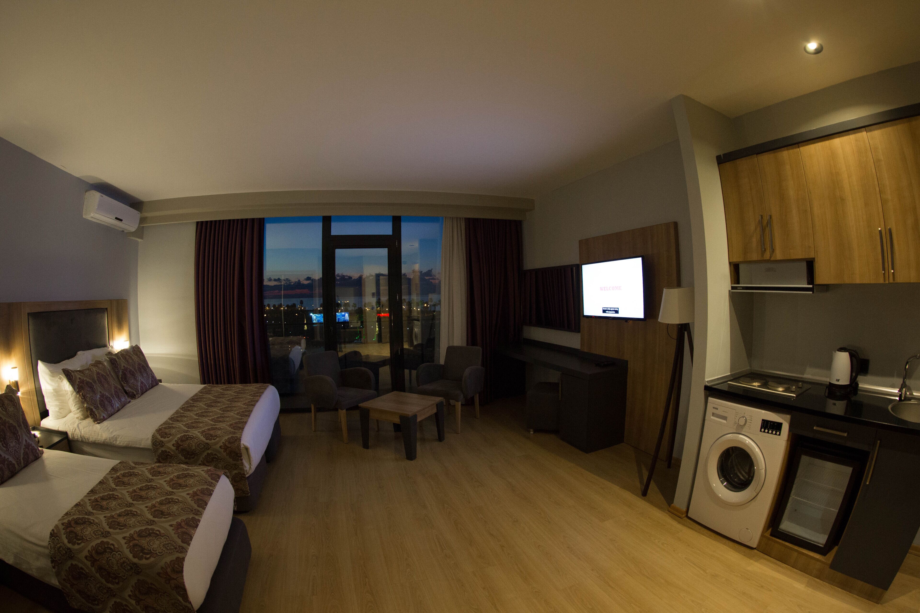 Une chambre d’hôtel avec deux lits, un coin salon, une télévision, un lave-linge et une vue sur la ville.