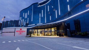 A modern hotel with a curved facade, large glass windows, and a prominent entrance.