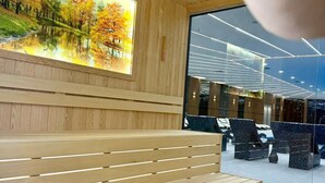 Un interior moderno con un banco de madera, un ventanal con una vista natural y una zona de estar con sillas.