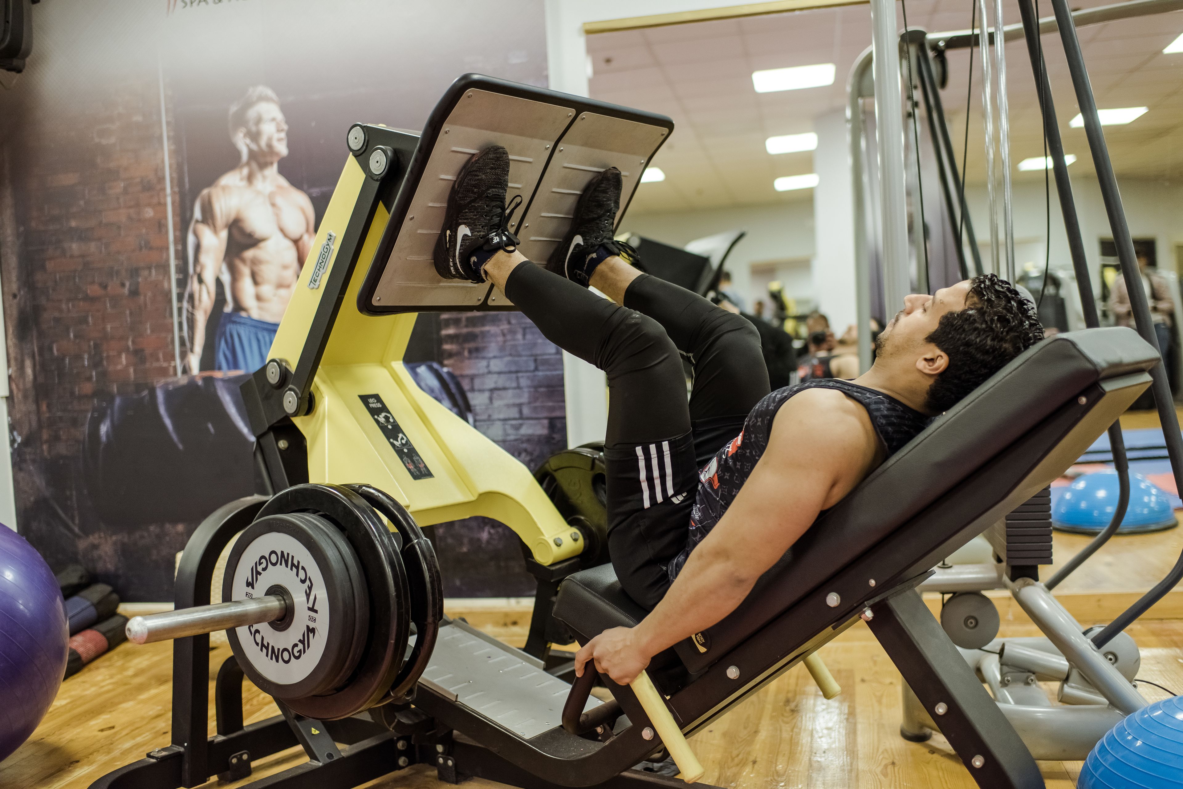 Un gimnasio con una persona usando una máquina de prensa de piernas.