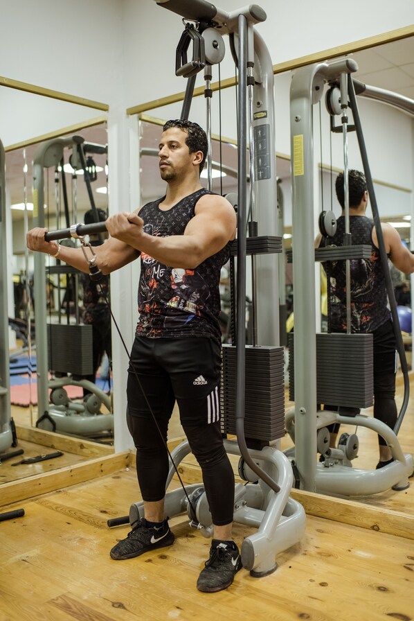 A gym with exercise equipment, wooden flooring, and mirrors.