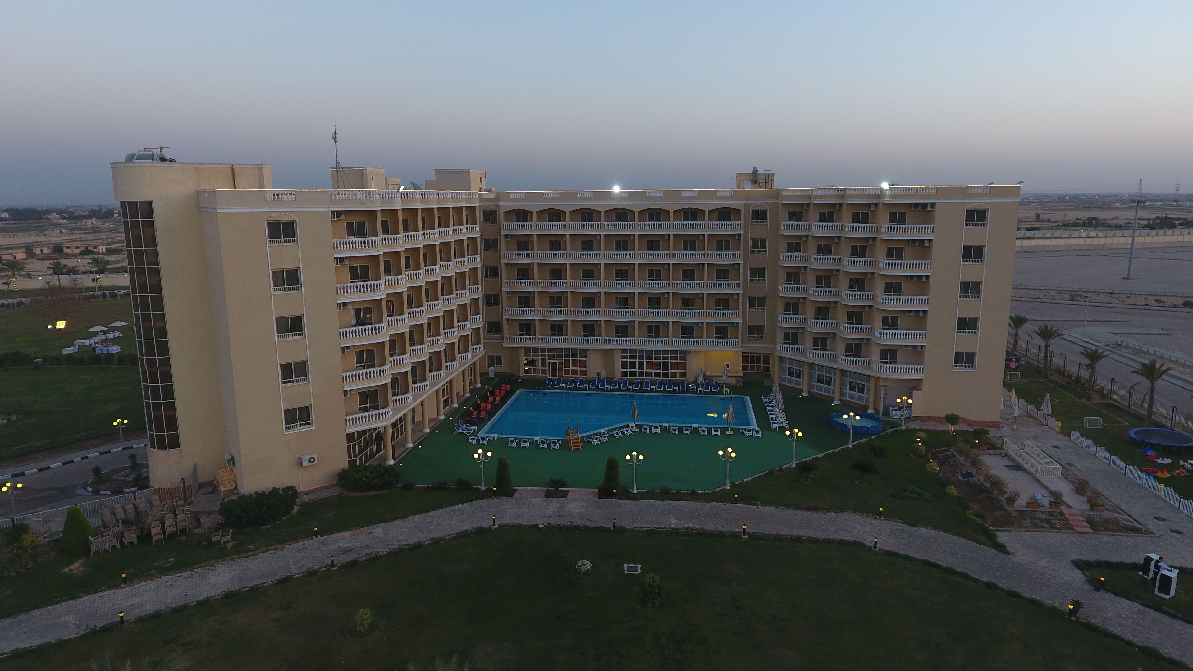 Un hotel de varios pisos con un patio central que cuenta con una piscina, rodeado de balcones y zonas de estar al aire libre.
