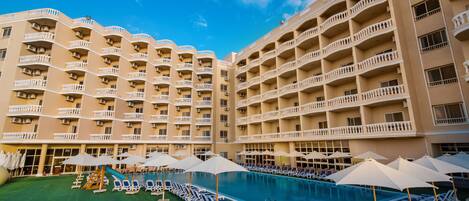 Una piscina al aire libre, sombrillas, sillones reclinables de piscina