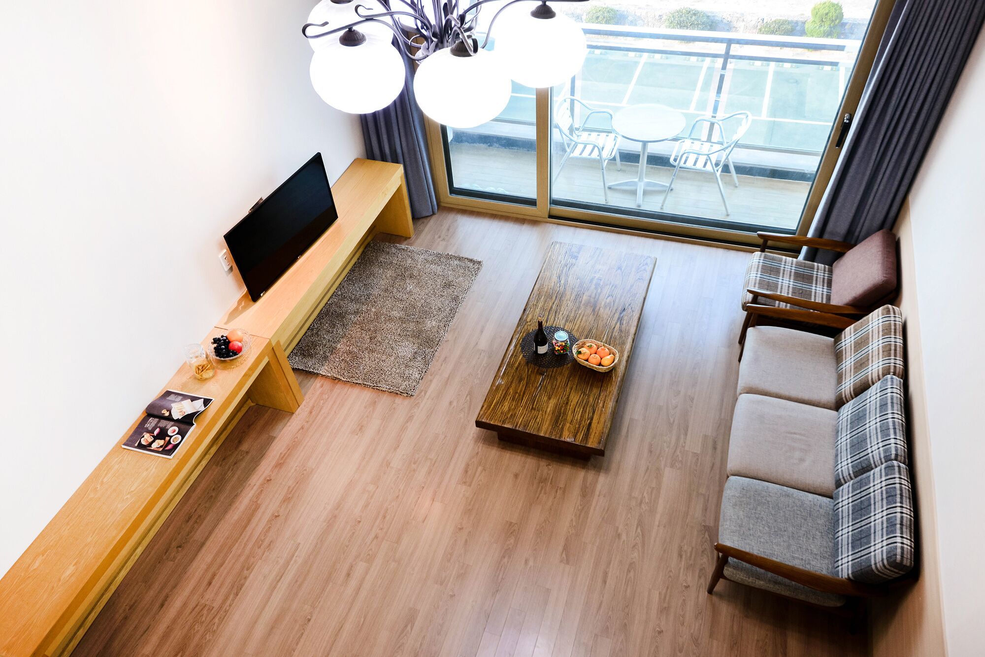 Un salon moderne avec une table basse en bois, un canapé, un téléviseur et un balcon aménagé avec du mobilier d’extérieur.
