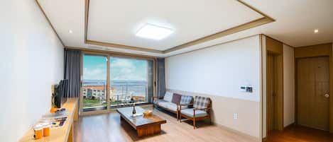 Una sala de estar moderna con un ventanal grande, un sofá, una mesita de centro y piso de madera.