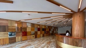 A modern reception area with a wooden panel wall, a marble floor, and a wooden reception desk. - Murex Plaza Hotel & Suites (Monrovia)