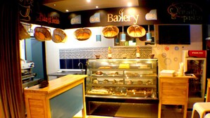 A bakery with a display case of baked goods, a counter, and a sign that reads "Bakery." - Murex Plaza Hotel & Suites (Monrovia)