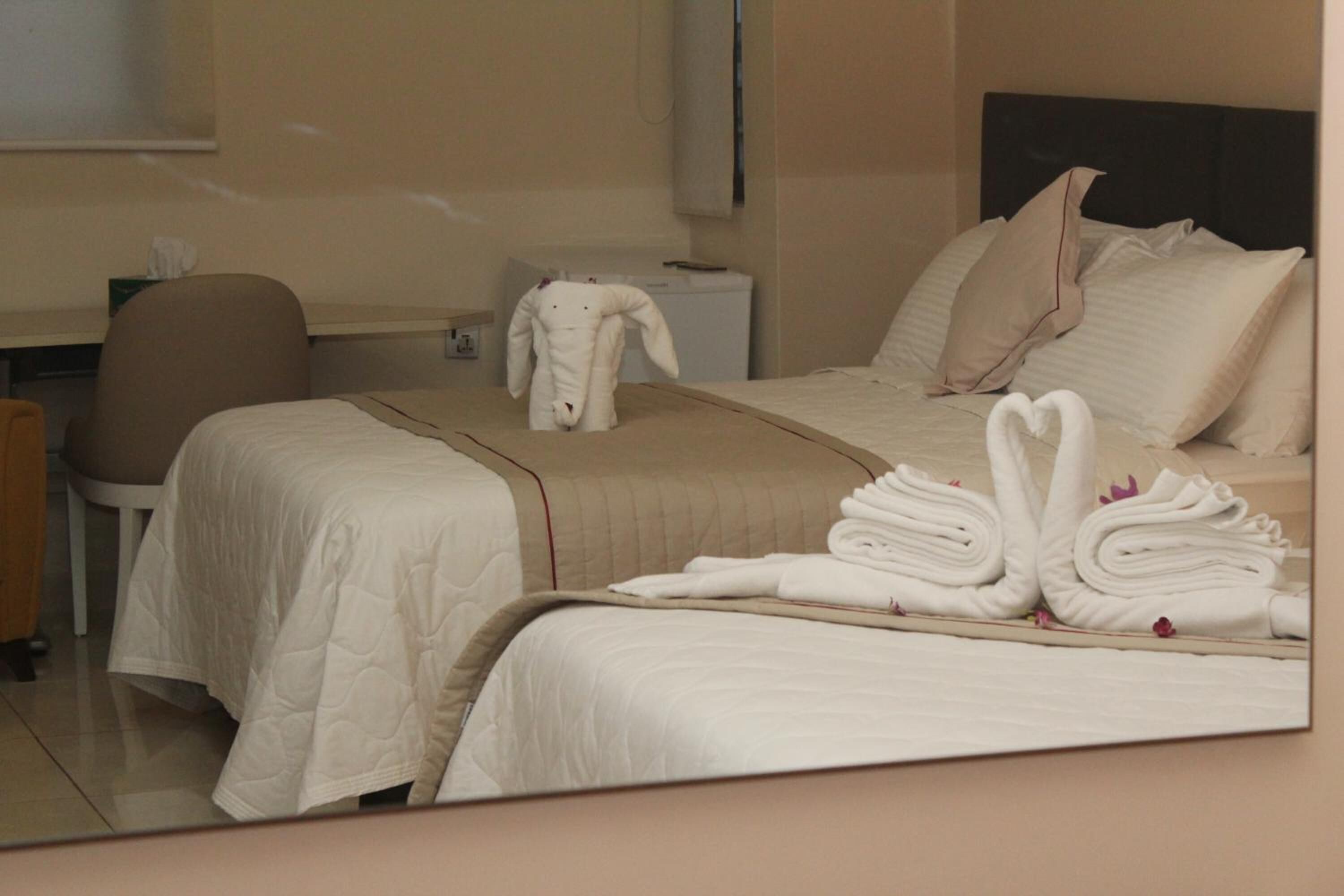 A hotel room with two beds, a desk, and a chair.