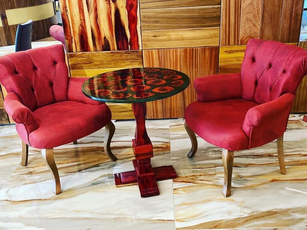 Une pièce comprenant deux fauteuils rouges à revêtement en tissu et une table ronde à surface réfléchissante.