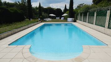 Una piscina al aire libre de temporada, sombrillas