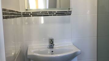 A bathroom with a white sink, a mirror above it, and a glass shower door.