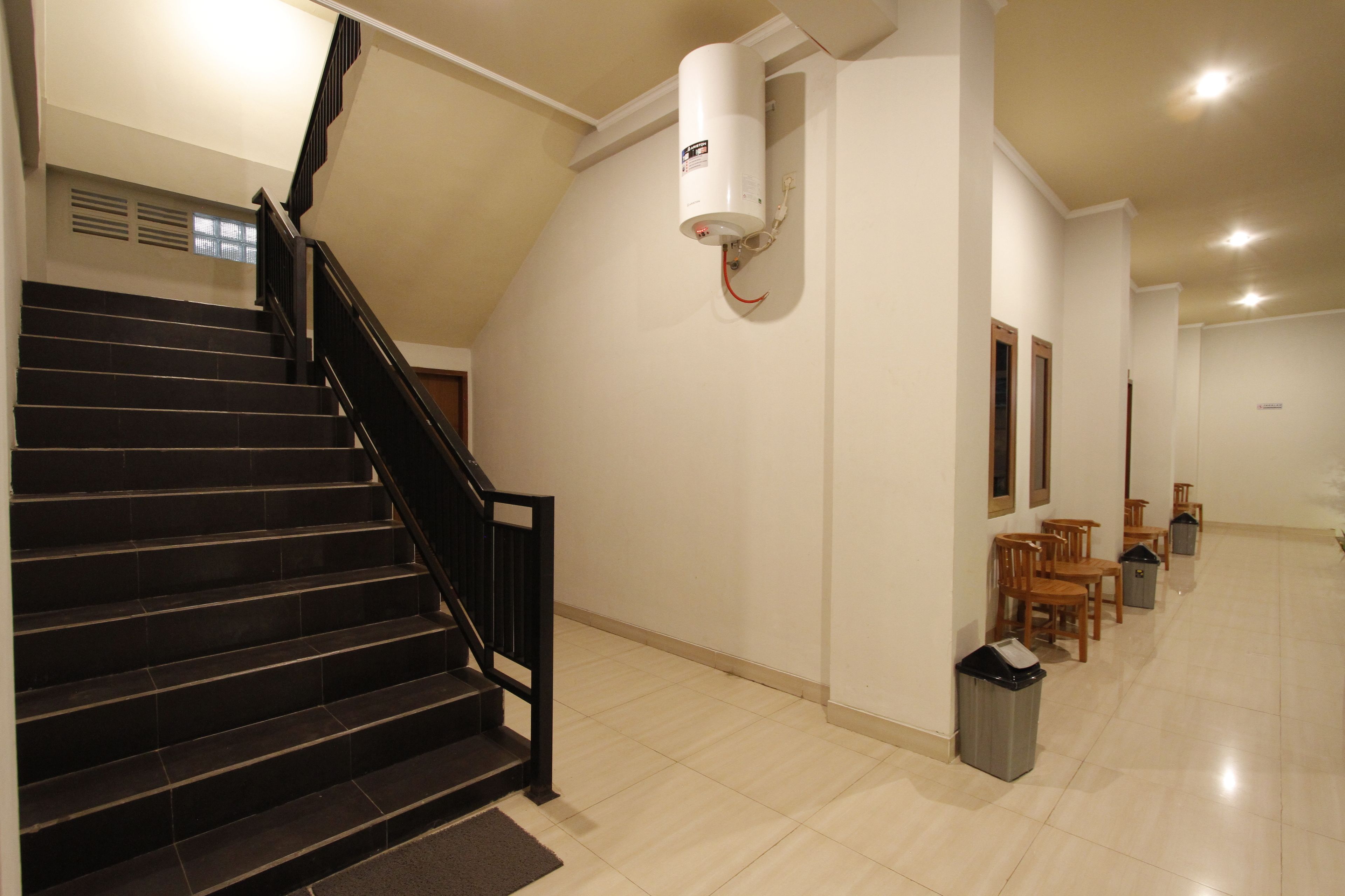 A staircase with black railings leading to a landing. A white cylindrical object is mounted on the wall above the stairs.