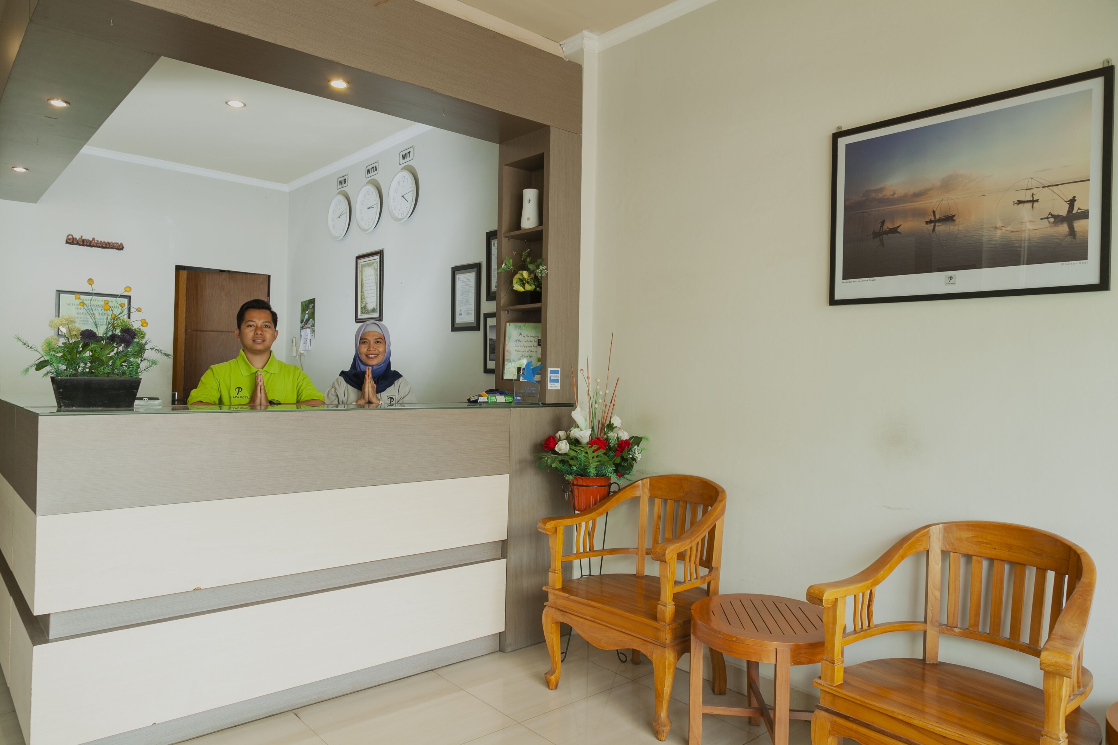 A reception area with a reception desk, two wooden chairs, a wall clock, and a framed picture.