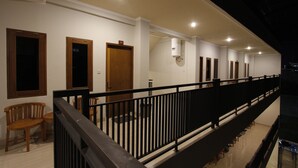 A hotel corridor with wooden doors, a black railing, and a ceiling with recessed lighting. - Palapa Hotel (Mataram)
